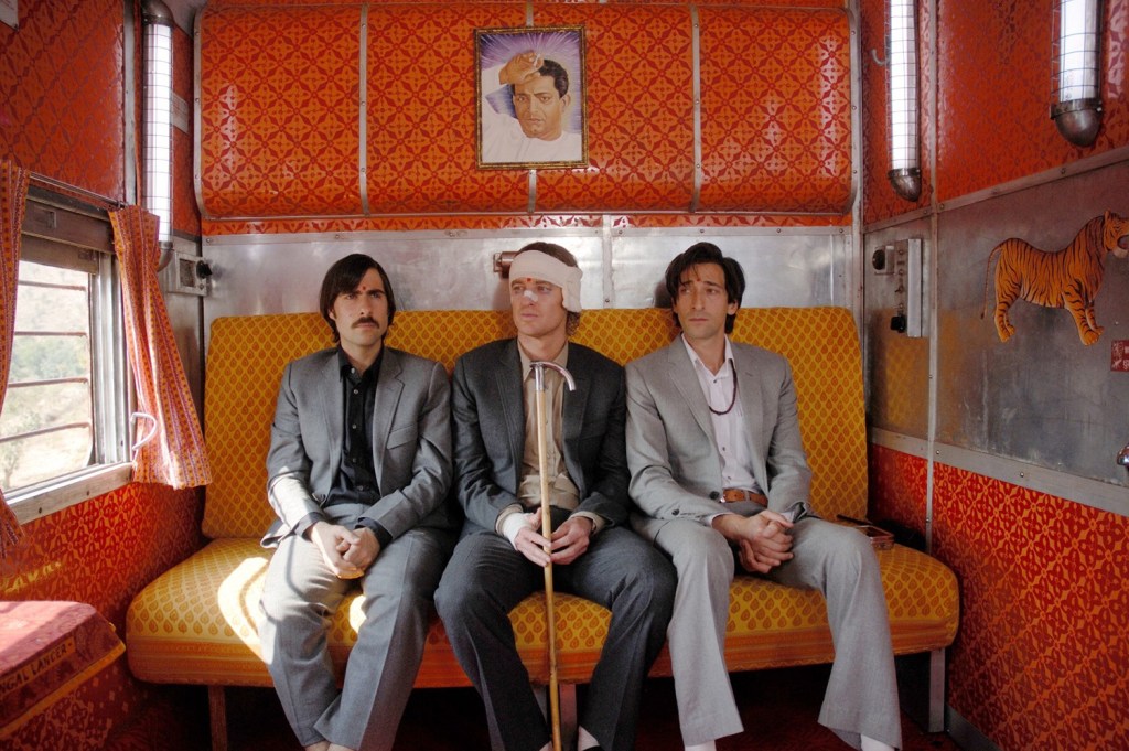 Les trois frères sur la banquette du train dans Darjeeling Unlimited — orange clair et orange foncé — Wes Anderson