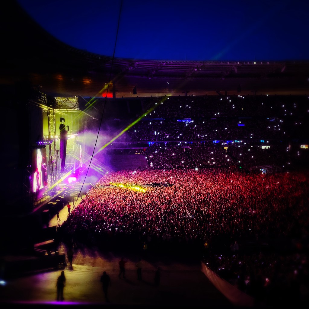 Concert de Depeche Mode le 24 juin 2023 — Stade de France — vue intérieure — les lumières sur le public — fumée jaune, rayons vert gazon et jaune d’or — reflets magenta