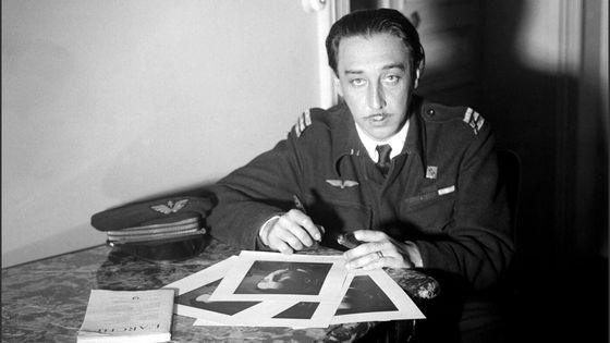 Romain Gary, regardant l'objectif, en uniforme de l'armée de l'air des Forces Françaises Libre signant des photographies de lui-même au moment de la parution de son premier roman, Education Européenne en 1945. Photo en noir et blanc. Illustration que j'ai choisie pour évoquer La promesse de l'aube de Romain Gary.