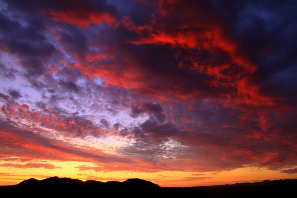 Paysage d'Arizona à la Mousson - Nuages roses et orange sous un ciel violet — montagnes noires au dessous